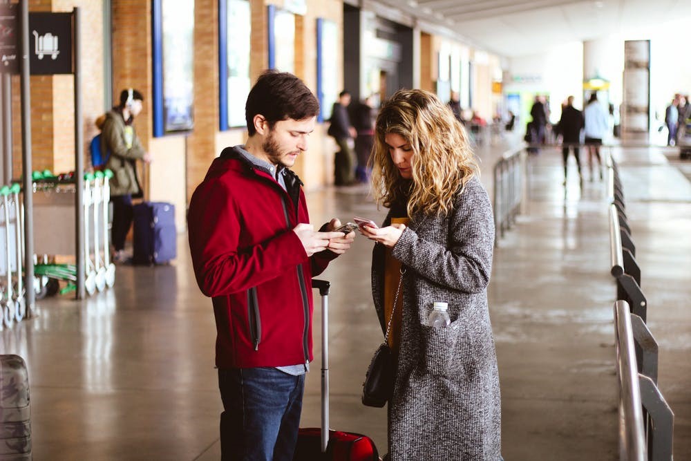 Una mujer y un hombre utilizando su móvil en un aeropuerto